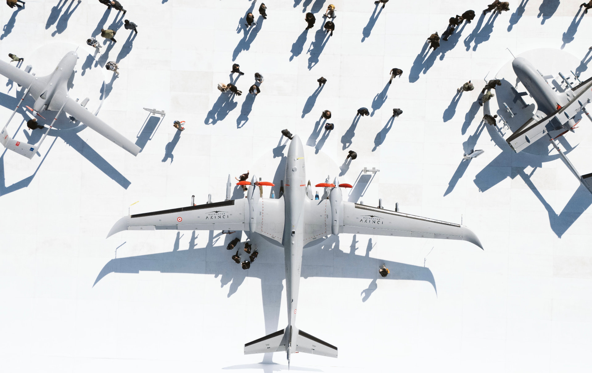 Top-down view of large drones on a bright apron surrounded by visitors