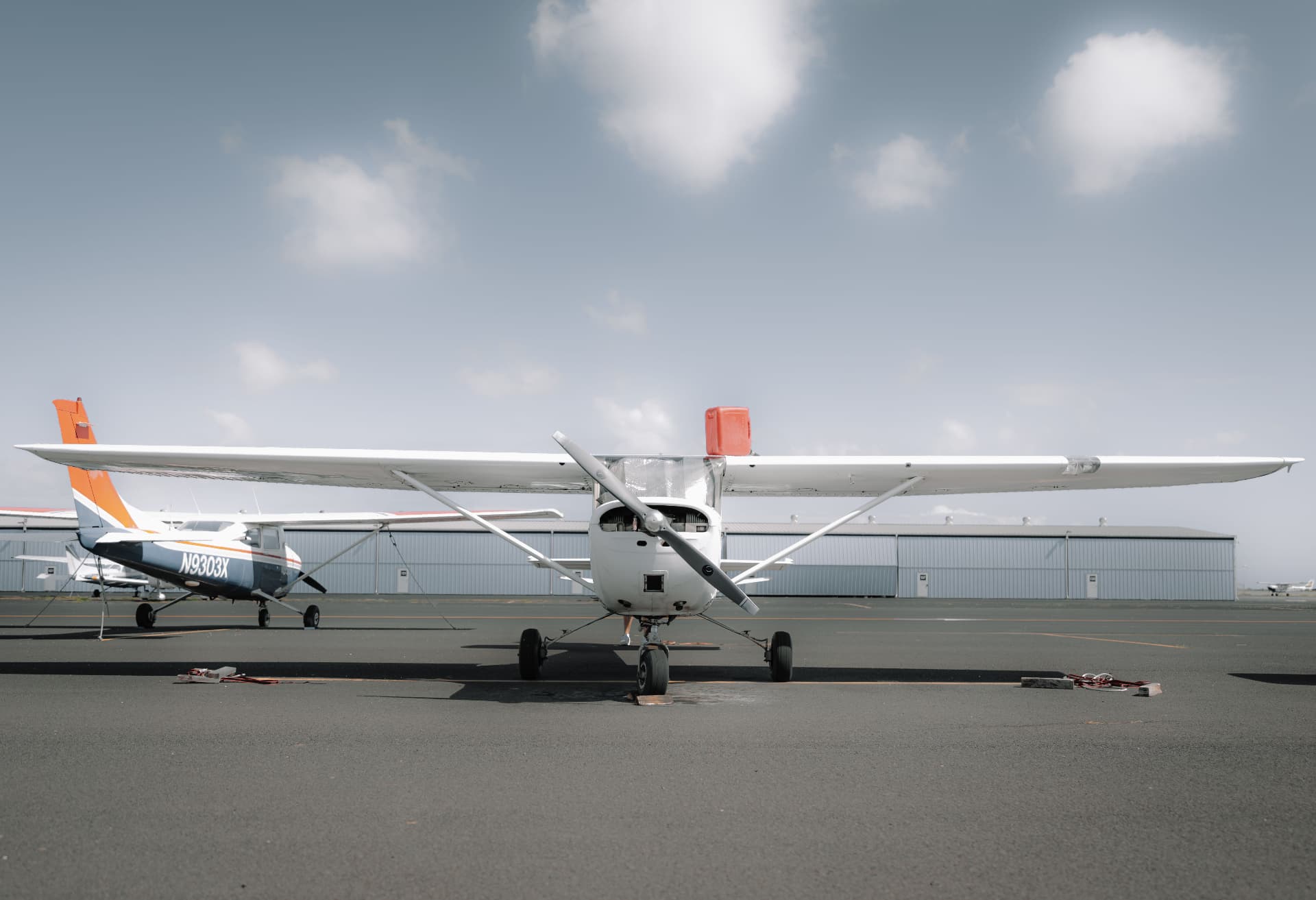 Single-engine Cessna parked on an airport apron under a bright sky