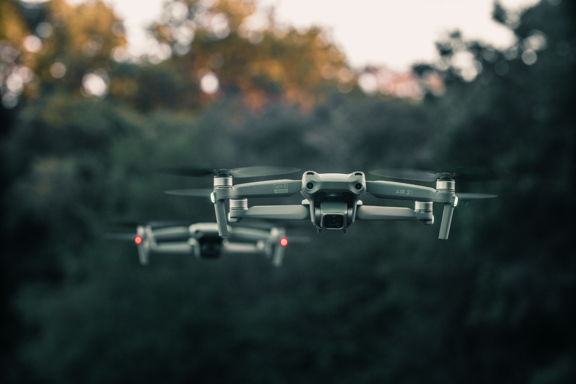 Camera drone hovering in a dark forest at dusk