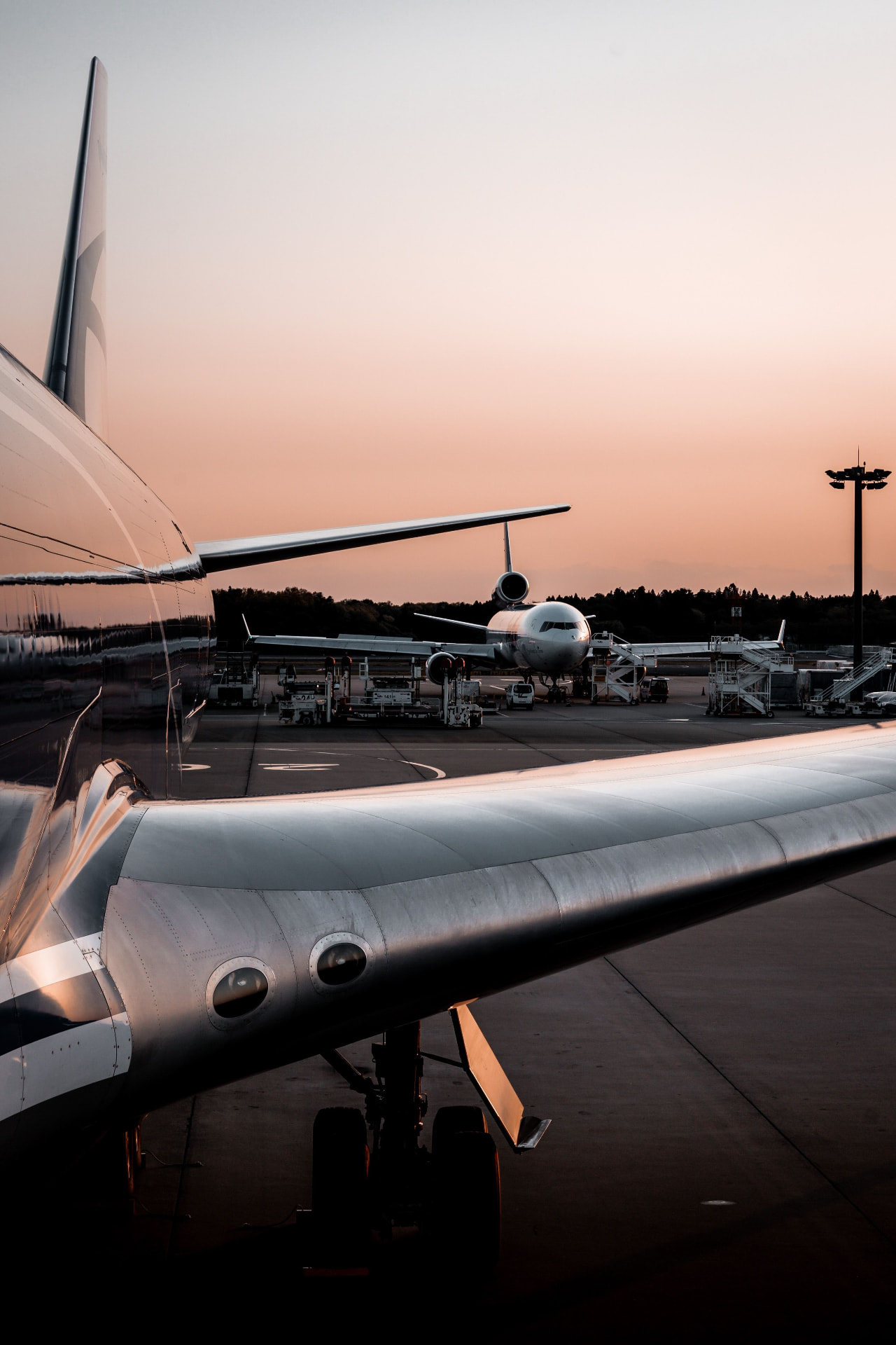 Aircraft wing and airliners on an airport apron at sunset
