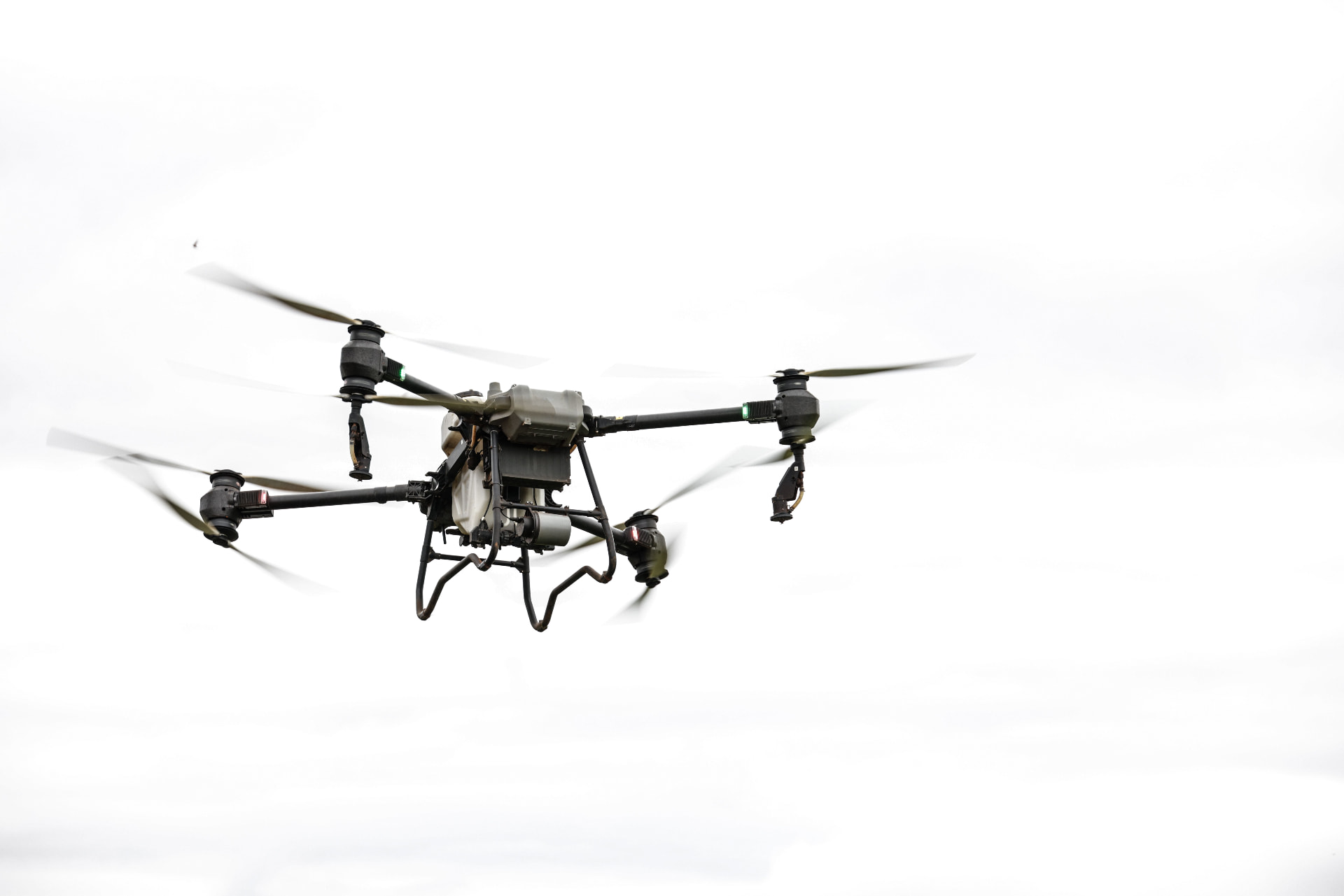 Commercial quadcopter drone in flight against a bright sky