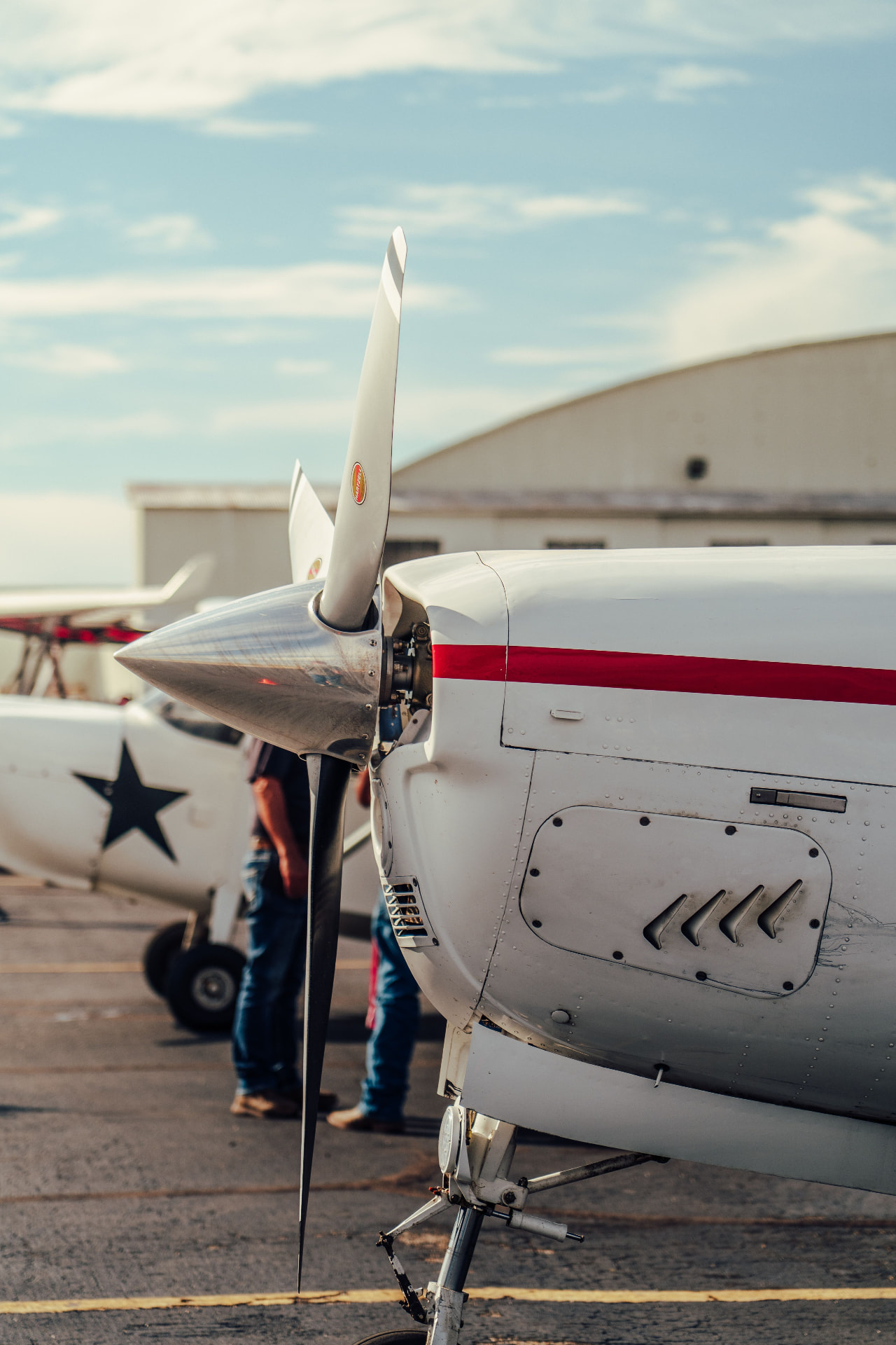 Nose and propeller of a light aircraft with a red stripe on the ramp
