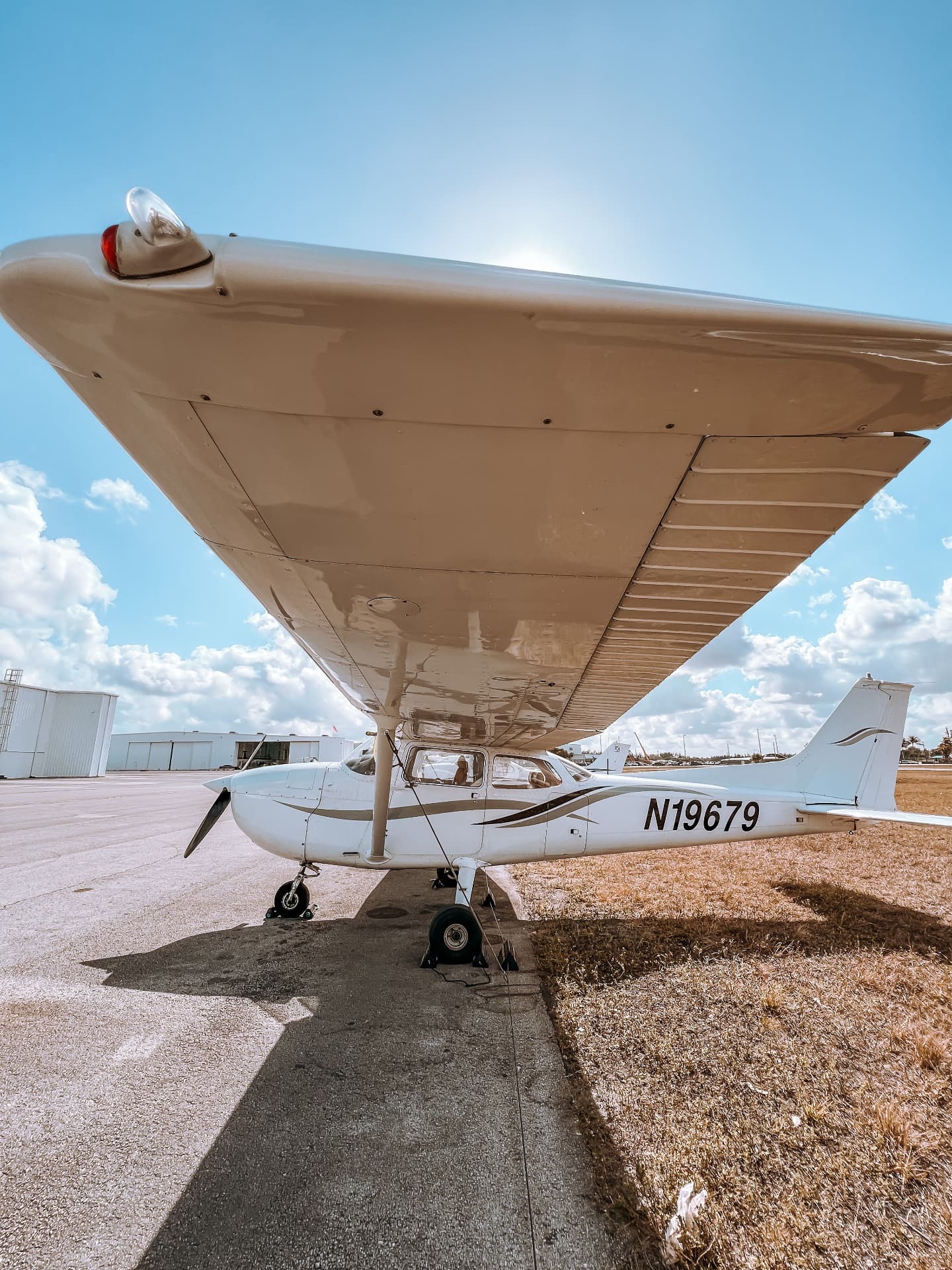 Single-engine Cessna parked on an apron seen from under the wing